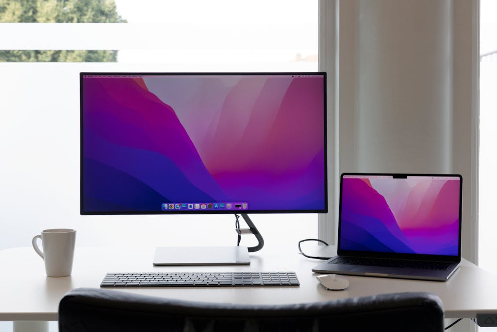 Minimalist workspace featuring dual monitors, keyboard, and a laptop on a clean desk.