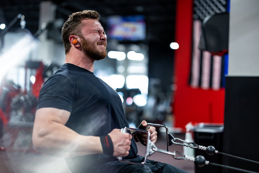 A muscular man in a gym performs an intense workout, emphasizing strength and focus.