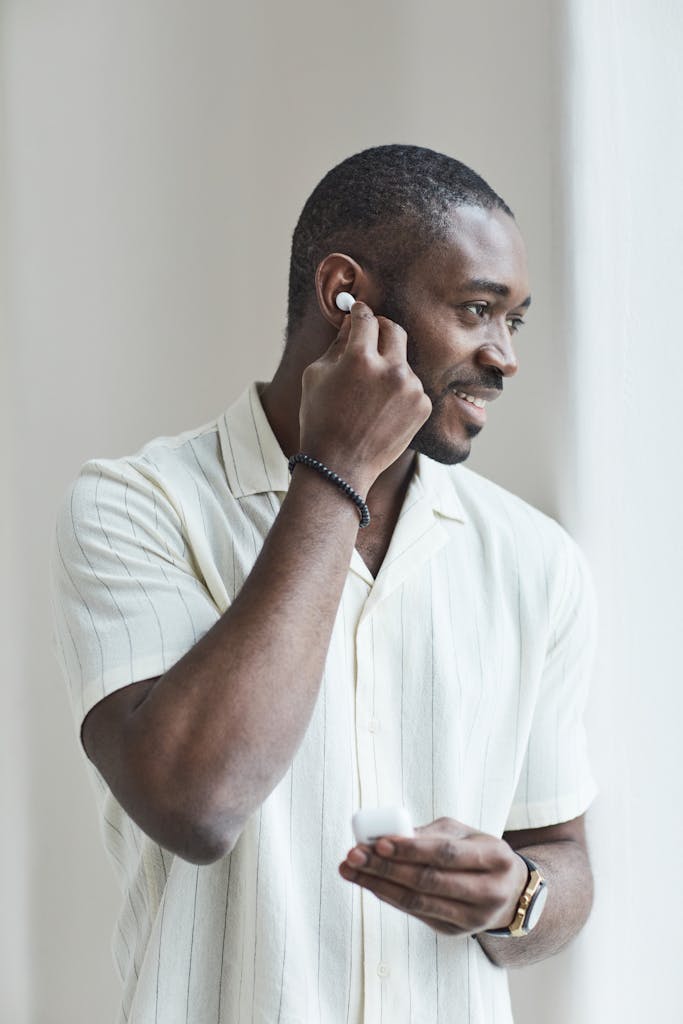 A smiling man enjoying music with wireless earphones indoors.