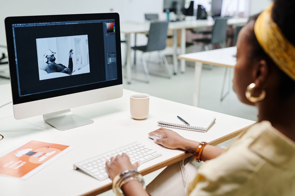 A woman using a computer for image editing in a bright, modern office setting.