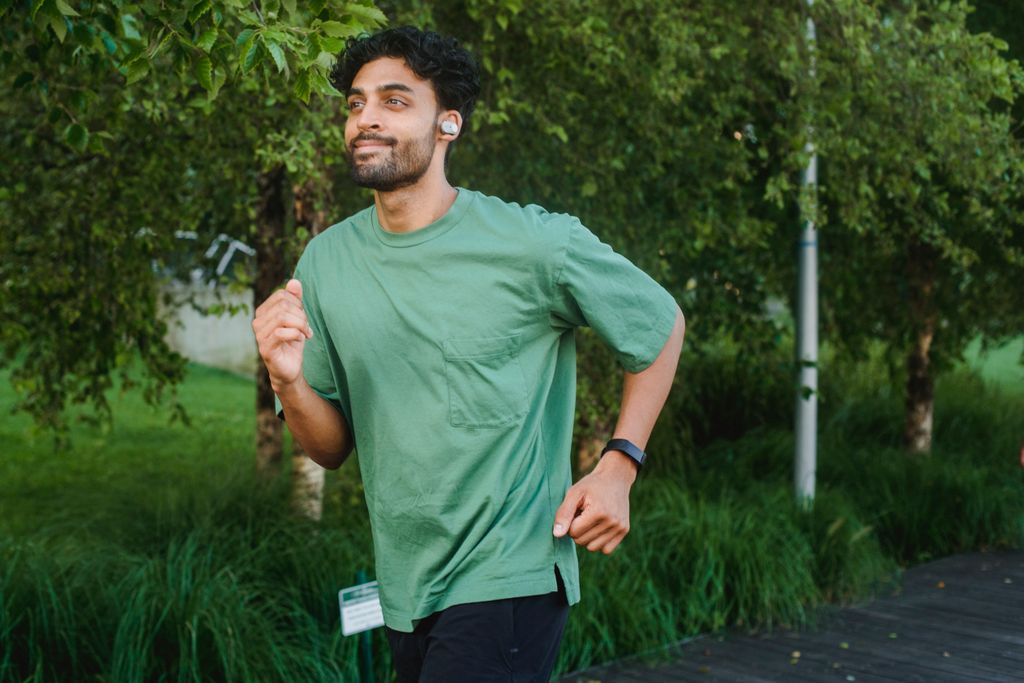 Adult male running outdoors in a lush park, embracing a healthy lifestyle.
