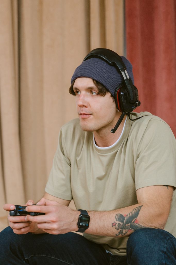 Casual gamer focused on playing video games indoors wearing a headset.