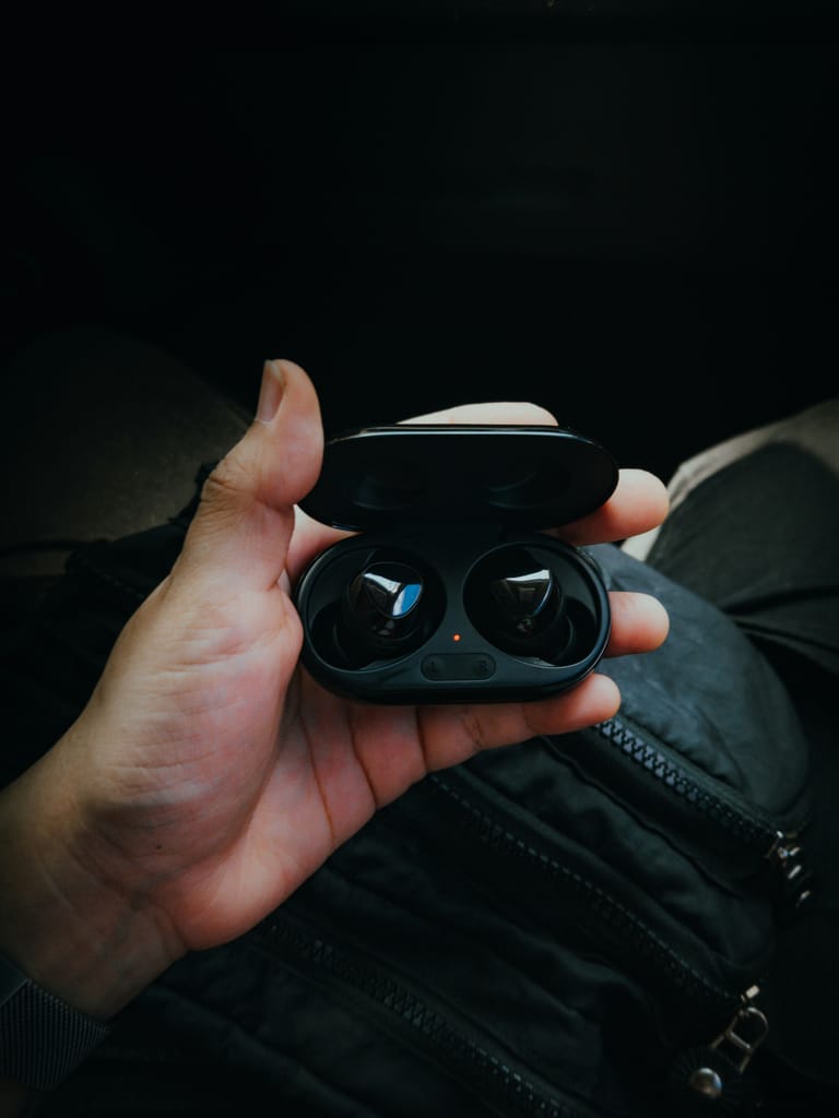 Close-up of a hand holding a pair of wireless earbuds in a charging case. Ideal for tech and lifestyle themes.