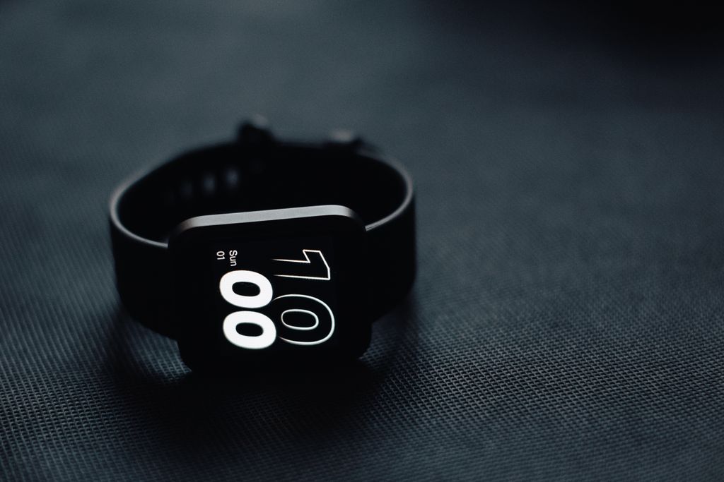 Modern smartwatch displaying time on a sleek dark gray surface, perfect for tech enthusiasts.