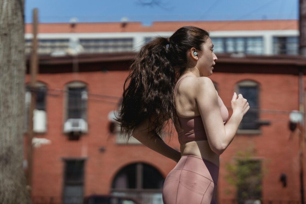 A woman jogging in an urban area on a sunny day, emphasizing active lifestyle and fitness.