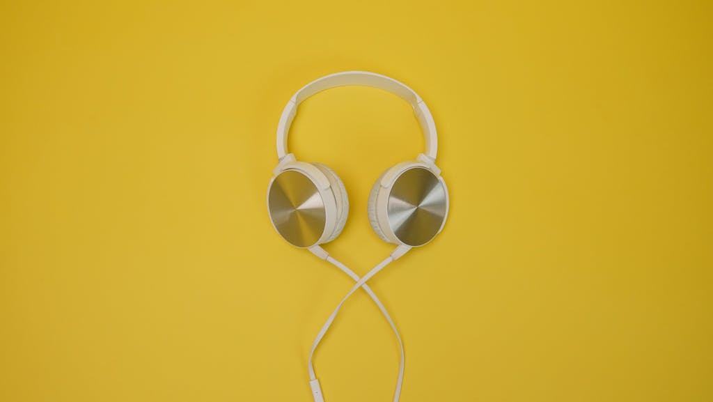 White and silver headphones displayed against a bright yellow backdrop, showcasing sleek design.